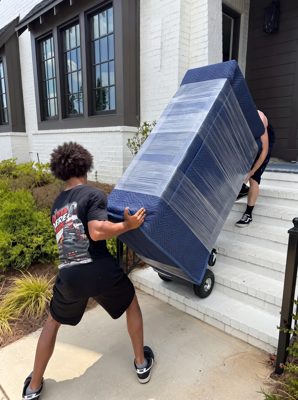 Outta Here Guys crew moving blanket-wrapped furniture on front steps